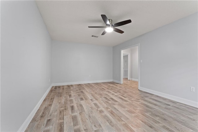 empty room featuring light wood-style floors, baseboards, ceiling fan, and visible vents