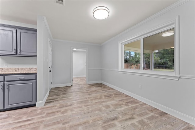 interior space with light wood-style floors, baseboards, ornamental molding, and visible vents