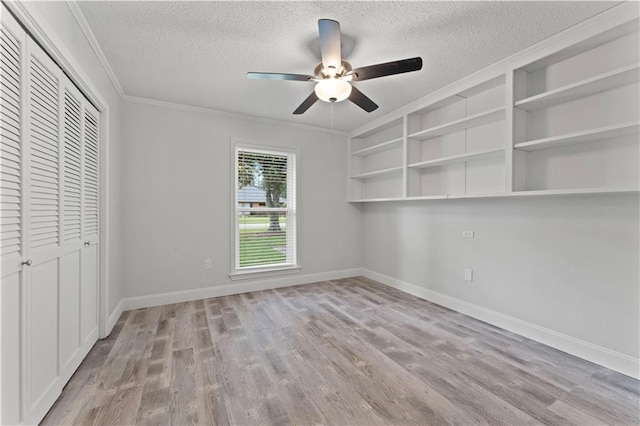 unfurnished bedroom featuring crown molding, baseboards, a textured ceiling, and wood finished floors
