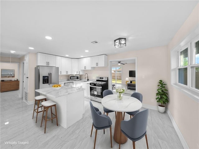 709 29th St, Kenner, LA 70062 - kitchen with a kitchen breakfast bar, a center island, white cabinets, appliances with stainless steel finishes, and a sink