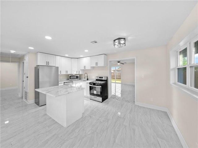 709 29th St, Kenner, LA 70062 - kitchen featuring baseboards, white cabinetry, a kitchen island, stainless steel appliances, and a sink