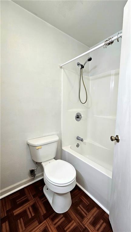 full bath with washtub / shower combination, toilet, and baseboards