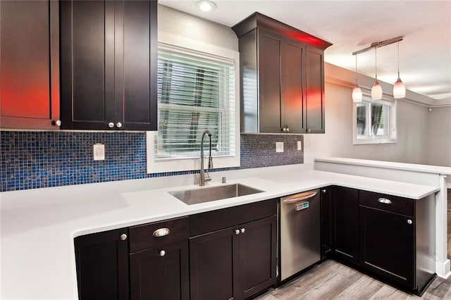 kitchen with tasteful backsplash, dishwasher, a sink, light countertops, and a peninsula