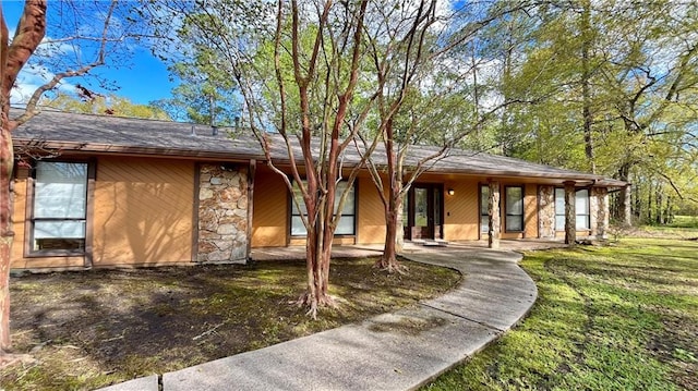 ranch-style home featuring stone siding and a front lawn