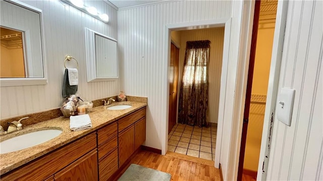 full bathroom with wood finished floors, double vanity, a sink, and a walk in closet