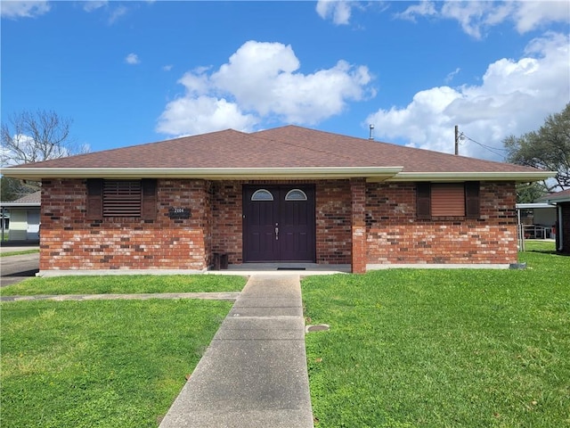 ranch-style house featuring brick siding, a front lawn, and a shingled roof