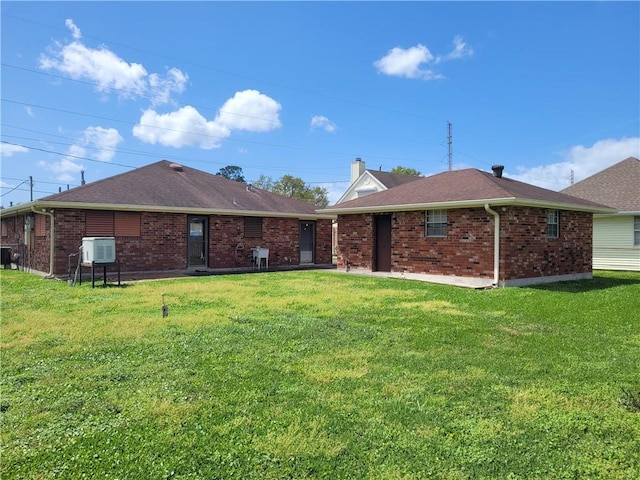 rear view of property featuring a yard and brick siding