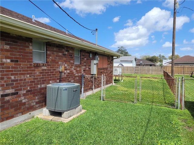 view of yard featuring a gate, fence, and central AC