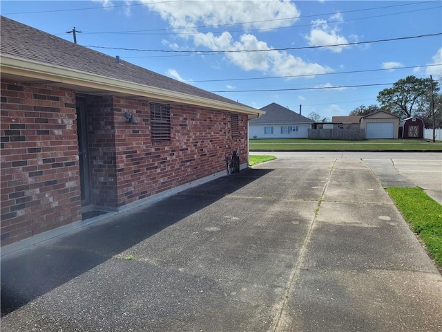 view of side of home with brick siding and an outdoor structure