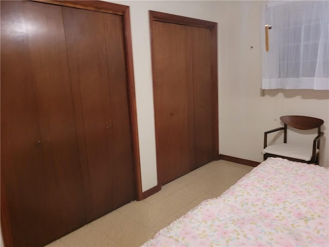 bedroom featuring two closets, baseboards, and light floors