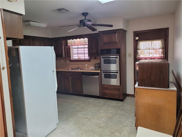 kitchen with appliances with stainless steel finishes, a ceiling fan, visible vents, decorative backsplash, and a sink