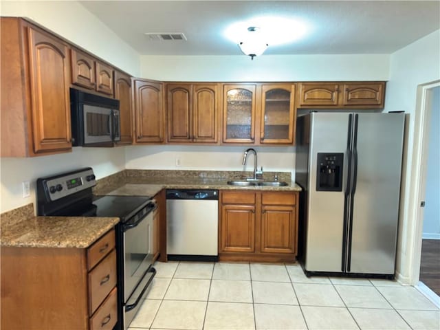 3403 W Loyola Dr, Kenner, LA 70065 - kitchen featuring appliances with stainless steel finishes, a sink, light tile patterned floors, and brown cabinetry