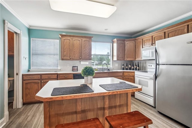 32875 Rivergate Cir Unit 28, Springfield, LA 70462 - kitchen featuring white appliances, light wood-style floors, crown molding, a center island, and light countertops