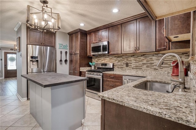 kitchen featuring a sink, appliances with stainless steel finishes, decorative backsplash, and dark brown cabinets