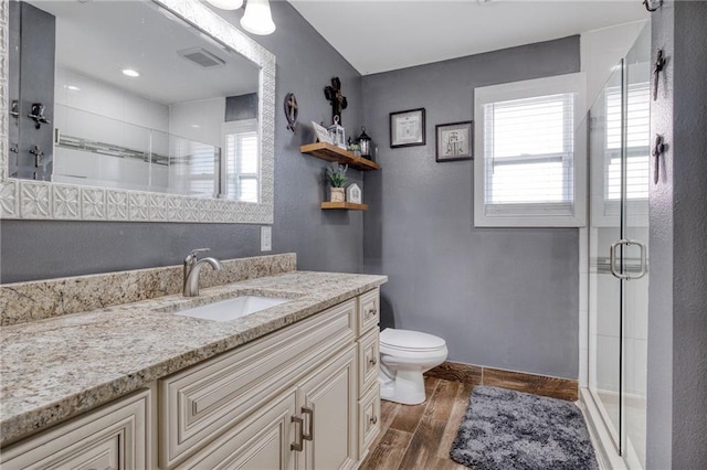 bathroom with toilet, a shower stall, wood finished floors, and vanity