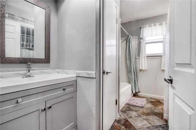 bathroom featuring vanity, baseboards, stone finish floor, and shower / bath combination with curtain
