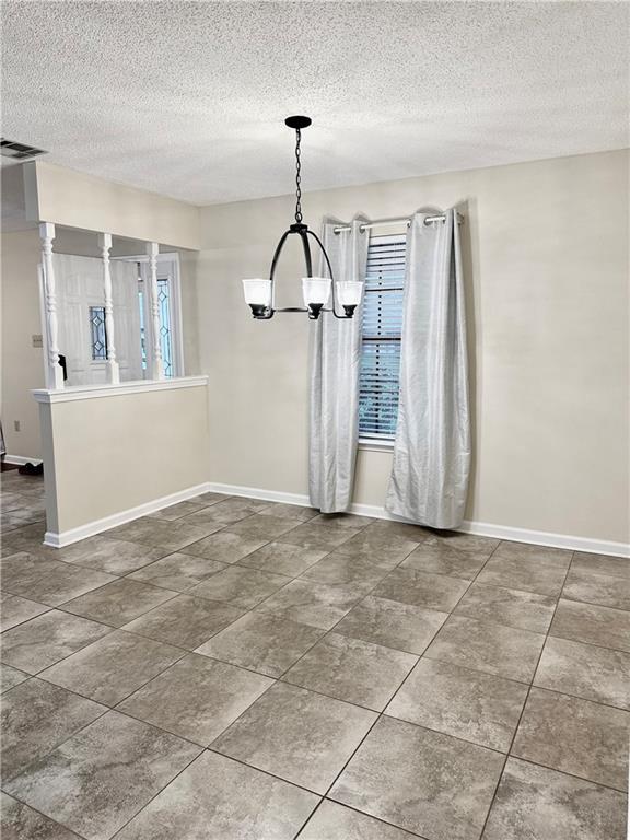 742 Central Ave, Reserve, LA 70084 - unfurnished dining area featuring a textured ceiling, visible vents, a notable chandelier, and baseboards