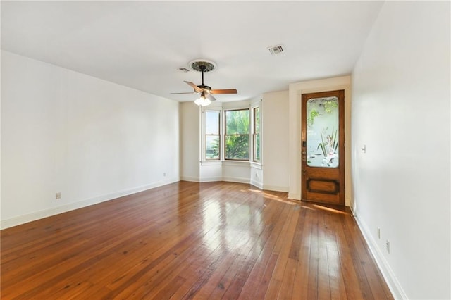 spare room with hardwood / wood-style floors, visible vents, baseboards, and a ceiling fan