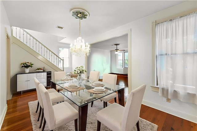 dining room with an inviting chandelier, visible vents, stairway, wood finished floors, and baseboards