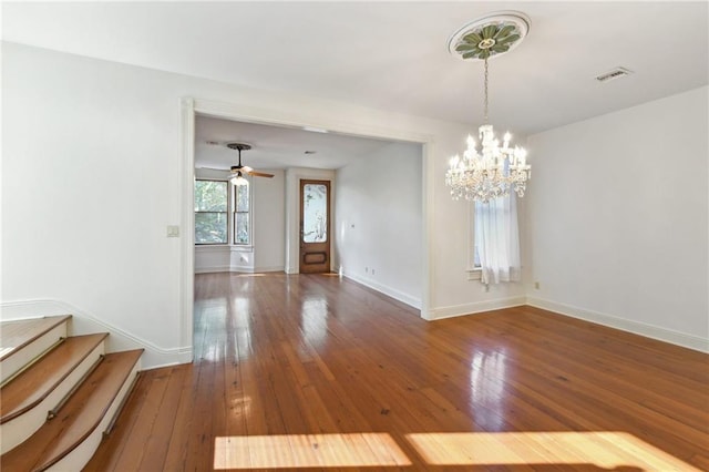 unfurnished dining area with visible vents, baseboards, an inviting chandelier, hardwood / wood-style flooring, and stairs