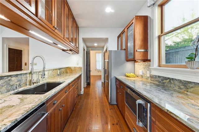 kitchen featuring a sink, appliances with stainless steel finishes, dark wood-style floors, brown cabinets, and backsplash