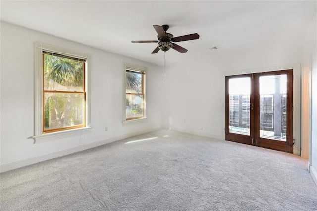 carpeted spare room with visible vents, a ceiling fan, and plenty of natural light