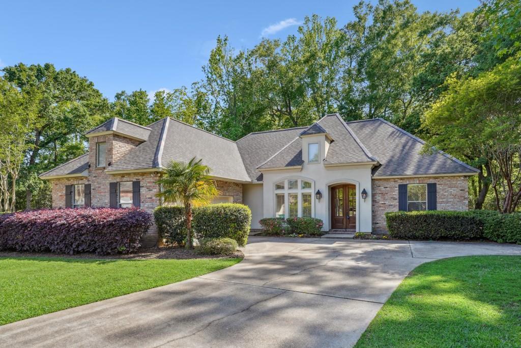french country style house with stucco siding, roof with shingles, a front yard, french doors, and driveway