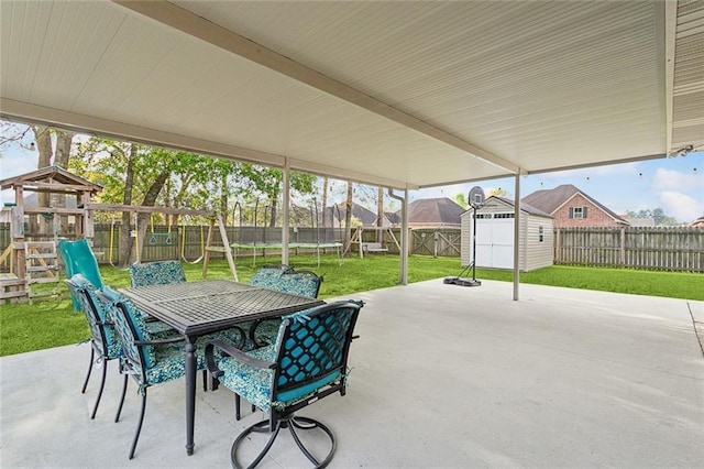 view of patio with a storage shed, a fenced backyard, a trampoline, and an outbuilding
