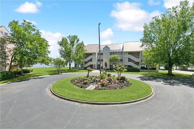 view of home's community featuring a lawn and curved driveway