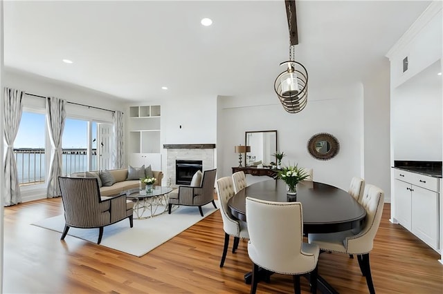 dining area with recessed lighting, a tiled fireplace, and light wood-type flooring