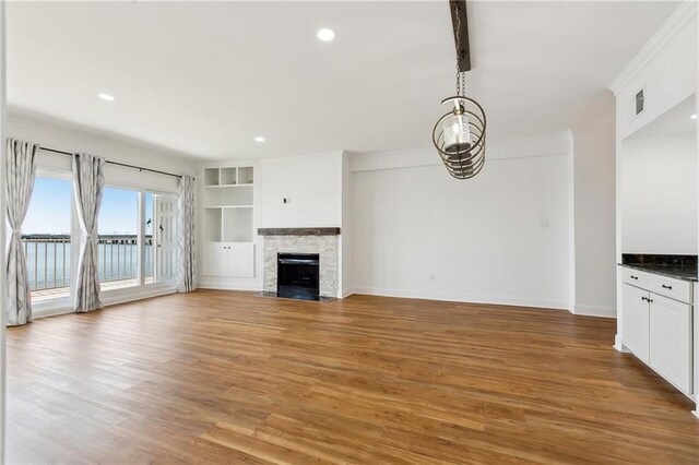 unfurnished living room featuring visible vents, a fireplace with flush hearth, baseboards, light wood-style floors, and recessed lighting