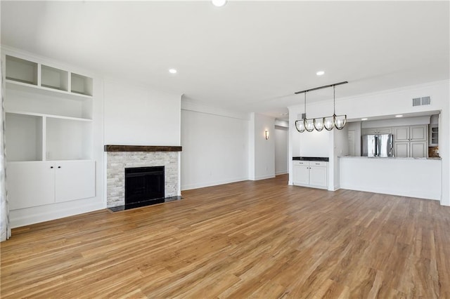 unfurnished living room featuring crown molding, a stone fireplace, recessed lighting, light wood-type flooring, and visible vents