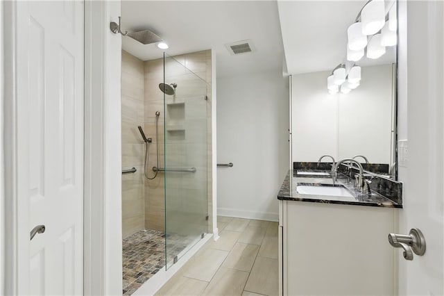 bathroom with visible vents, a sink, double vanity, and a shower stall