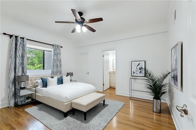 bedroom with light wood-style floors, baseboards, ceiling fan, and ensuite bathroom