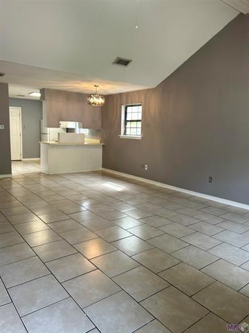 158-160 Beech St, Covington, LA 70443 - unfurnished living room featuring light tile patterned flooring, baseboards, an inviting chandelier, and visible vents