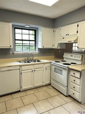 kitchen with white cabinets, a sink, white appliances, a textured ceiling, and under cabinet range hood