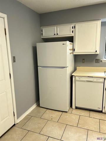 kitchen featuring light countertops, light tile patterned floors, white cabinets, and white appliances