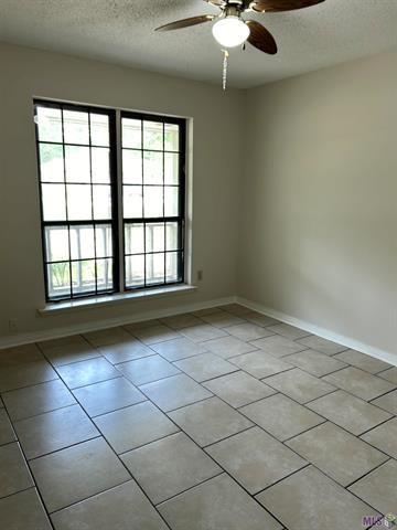 spare room with a ceiling fan, a textured ceiling, and a healthy amount of sunlight
