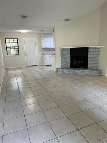 158-160 Beech St, Covington, LA 70443 - unfurnished living room featuring light tile patterned floors, baseboards, a fireplace, and visible vents