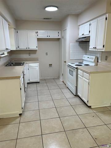 158-160 Beech St, Covington, LA 70443 - kitchen featuring white cabinetry, light countertops, white range with electric stovetop, under cabinet range hood, and light tile patterned flooring