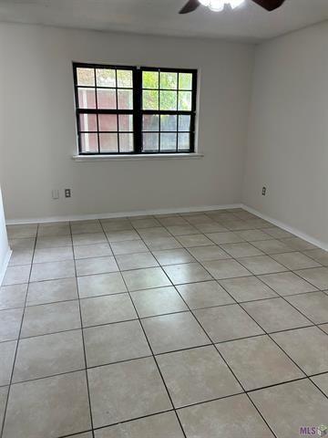 spare room featuring light tile patterned flooring, ceiling fan, plenty of natural light, and baseboards