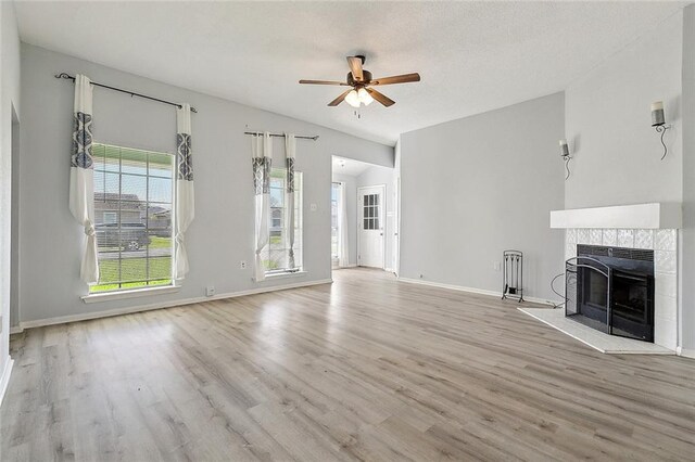 unfurnished living room with baseboards, ceiling fan, a fireplace, wood finished floors, and lofted ceiling