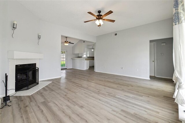 unfurnished living room featuring light wood-style floors, ceiling fan, a fireplace, visible vents, and baseboards