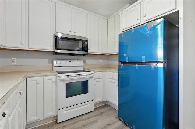 kitchen with freestanding refrigerator, light wood-style floors, electric stove, stainless steel microwave, and white cabinetry