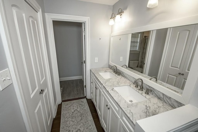 624 Fleurie Dr, Kenner, LA 70065 - bathroom featuring double vanity, a sink, toilet, and wood finished floors