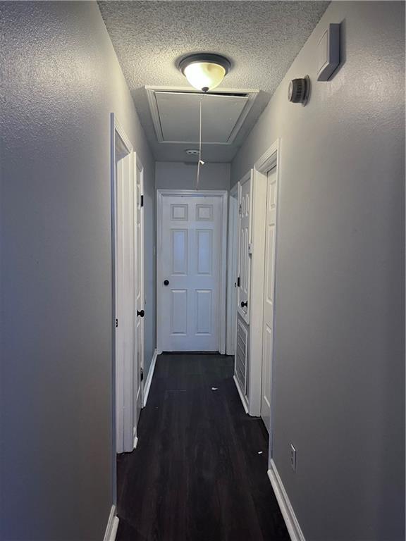 1921 Cartier Dr, La Place, LA 70068 - hallway with a textured ceiling, dark wood-style floors, baseboards, and attic access