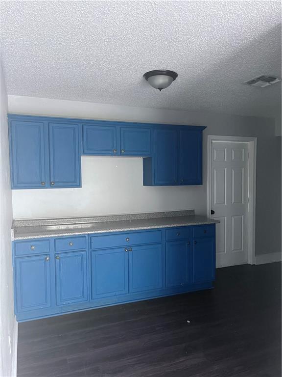 1921 Cartier Dr, La Place, LA 70068 - kitchen featuring visible vents, blue cabinetry, a textured ceiling, and dark wood-style floors
