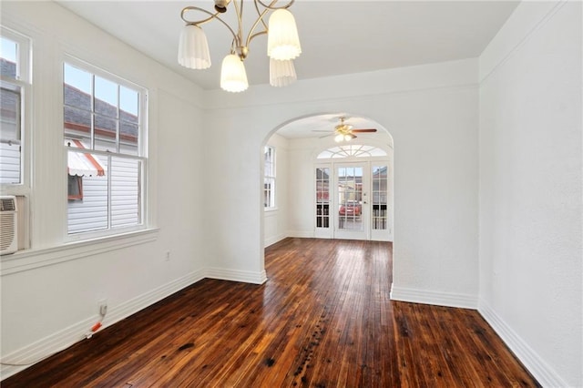 spare room with a healthy amount of sunlight, arched walkways, baseboards, and hardwood / wood-style floors