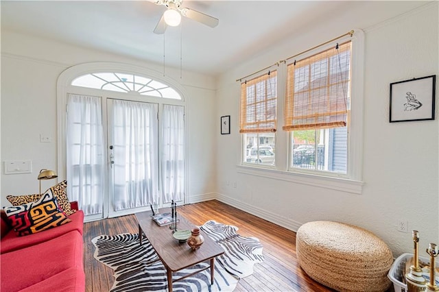 living area featuring baseboards, a ceiling fan, and wood finished floors