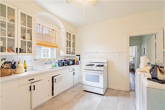 kitchen with ceiling fan, a sink, light countertops, washer / clothes dryer, and white range with gas stovetop